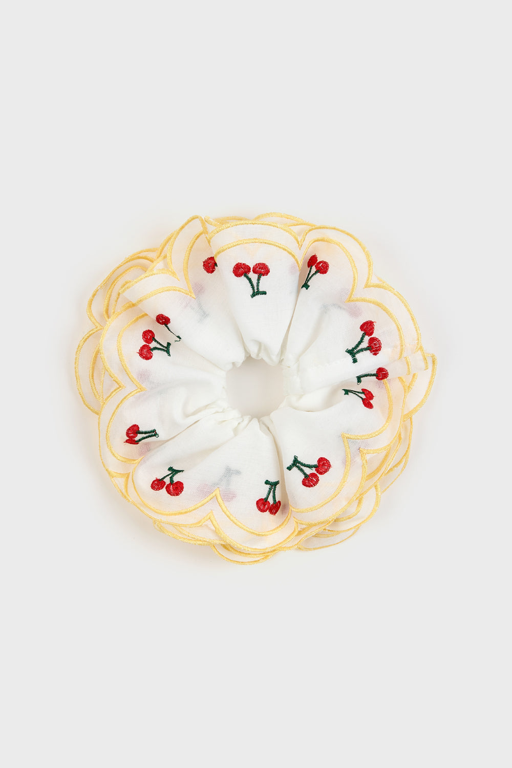 White scrunchie with embroidered red cherries and green stems, featuring a scalloped yellow edge design